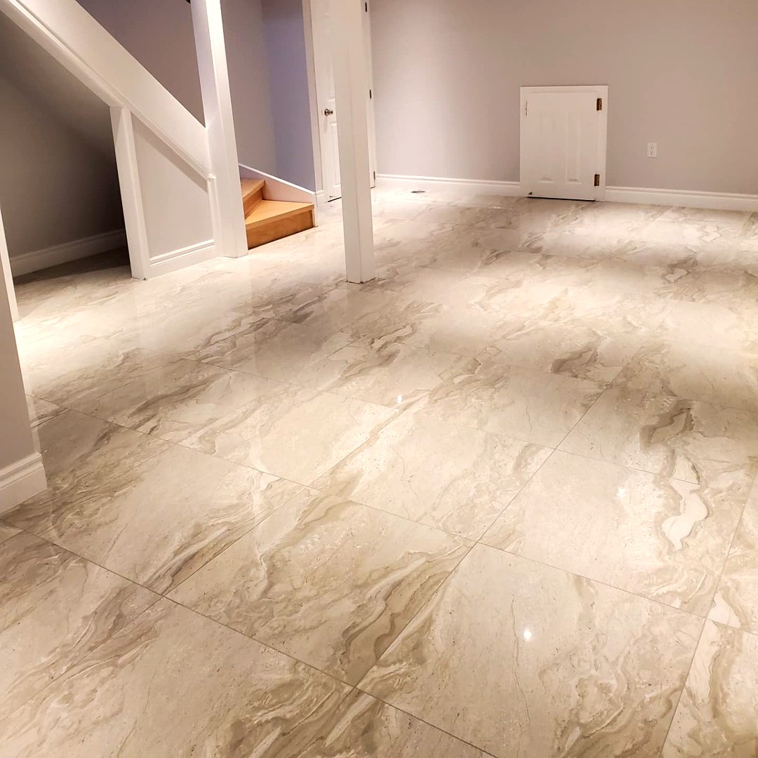 Finished basement with large-format marble-look tile flooring and staircase