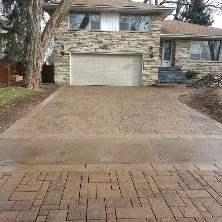New interlocking paver driveway in front of a stone-clad two-storey home